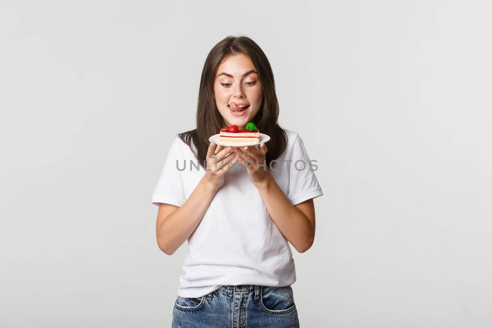 Portrait of tempted beautiful girl licking lips as looking at cake by Benzoix