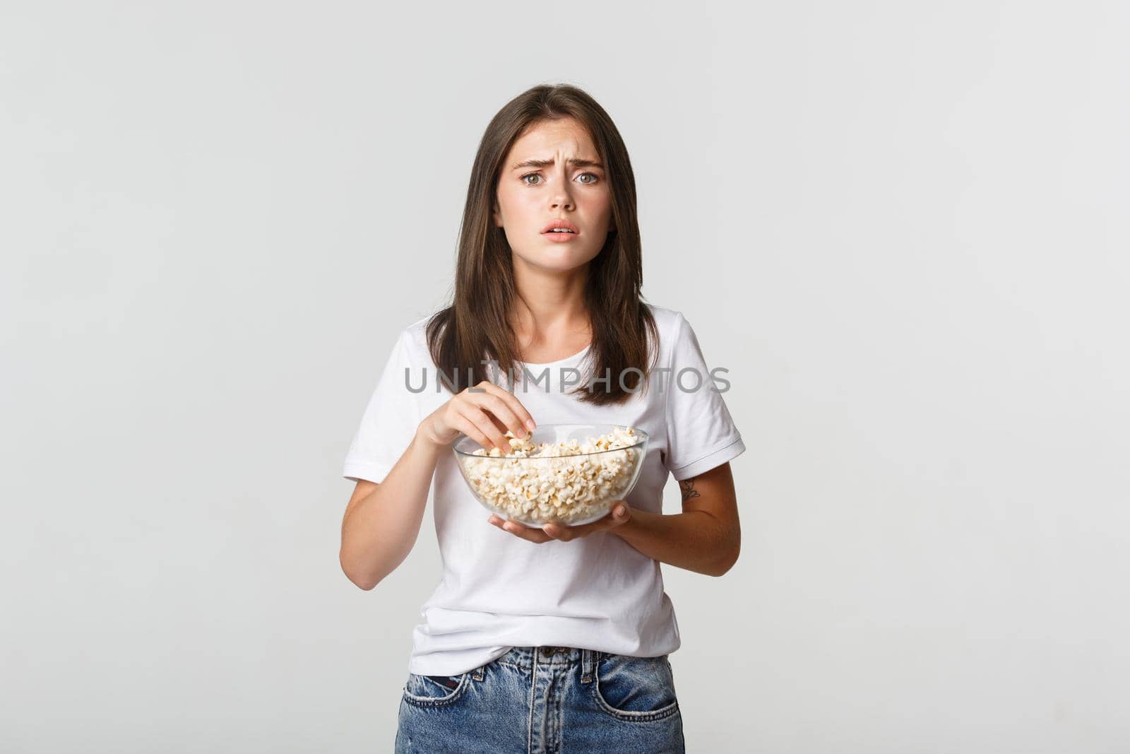 Portrait of compassionate young woman watching heartwarming movie, eating popcorn.