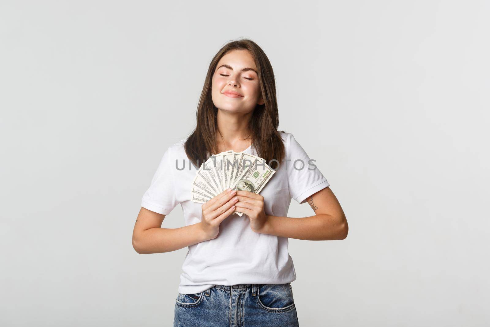 Happy and satisfied smiling woman close eyes and enjoying having money by Benzoix
