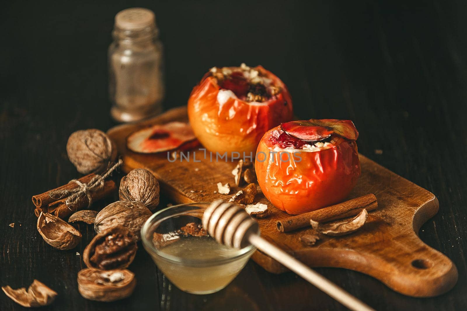 baked apples with cottage cheese with berries and nuts, topped with honey and sprinkled with cinnamon. on a wooden surface in a rustic style