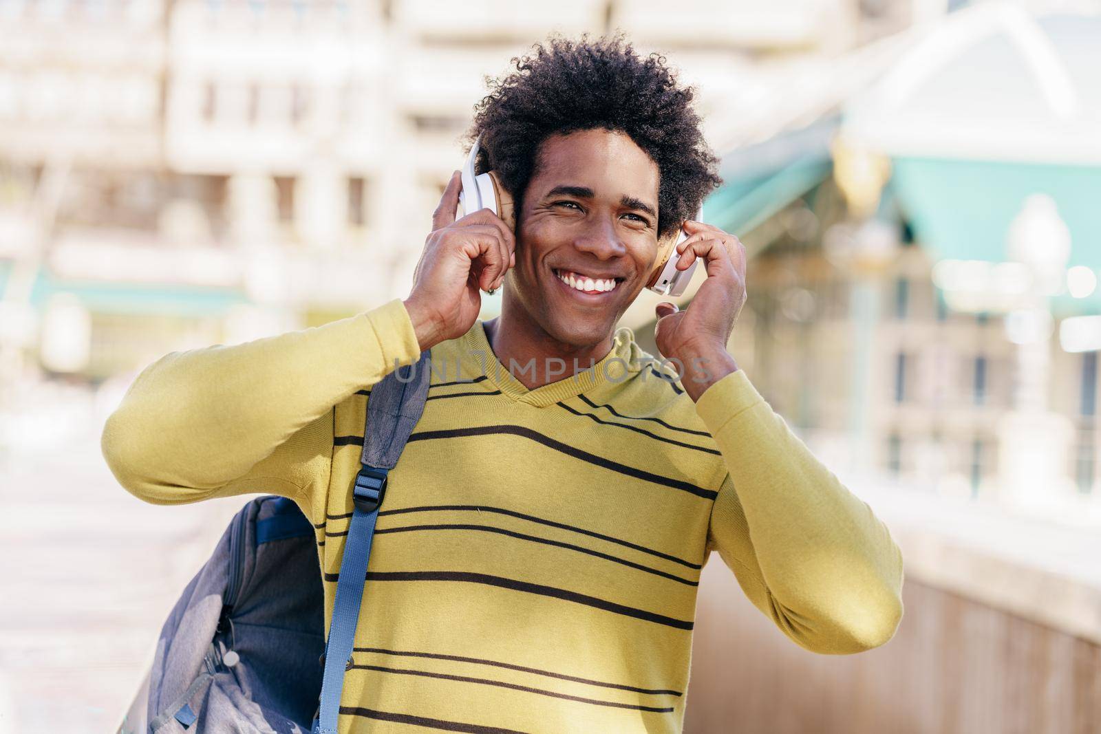 Black man listening to music with wireless headphones sightseeing in Granada by javiindy