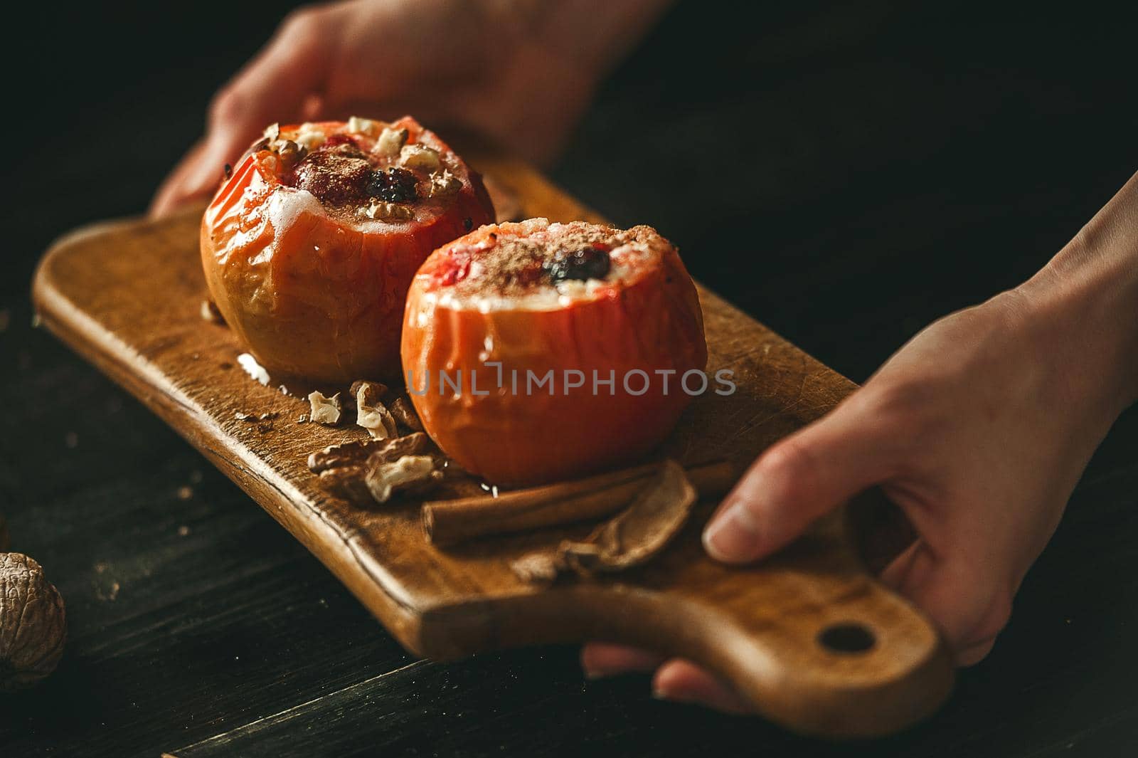 baked apples with cottage cheese with berries and nuts, topped with honey and sprinkled with cinnamon. on a wooden surface in a rustic style