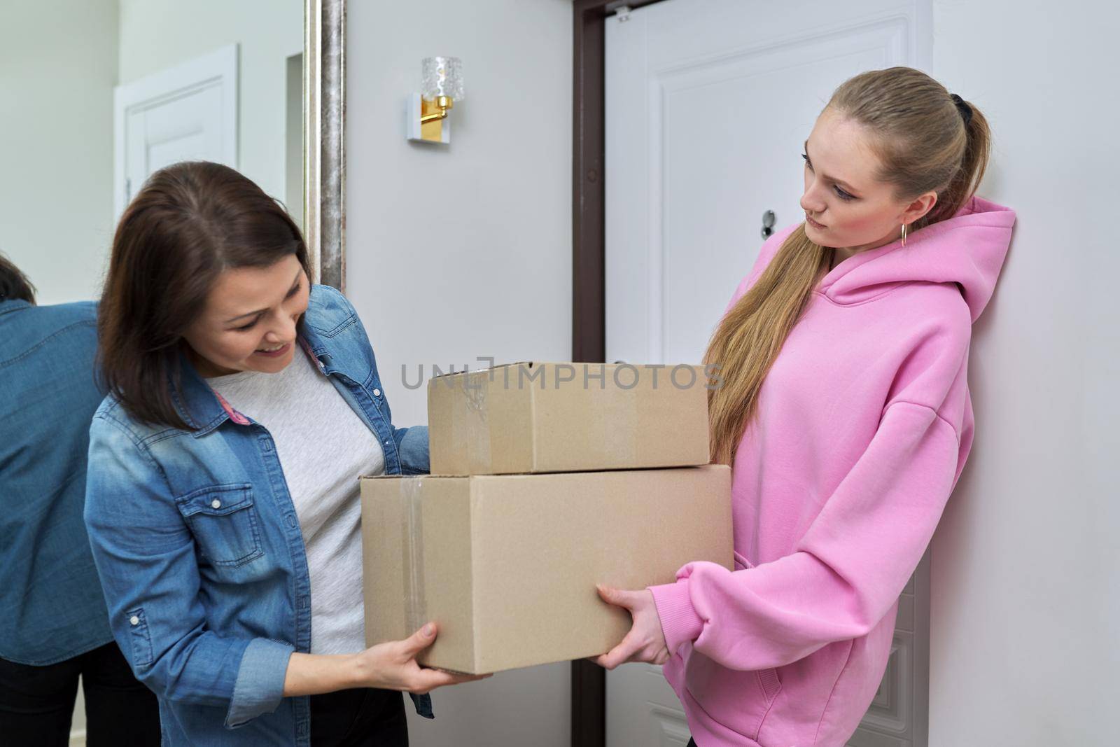 Delivery of goods, social services, post, home, lifestyle, online shopping. Two women with cardboard boxes near the front door of the house