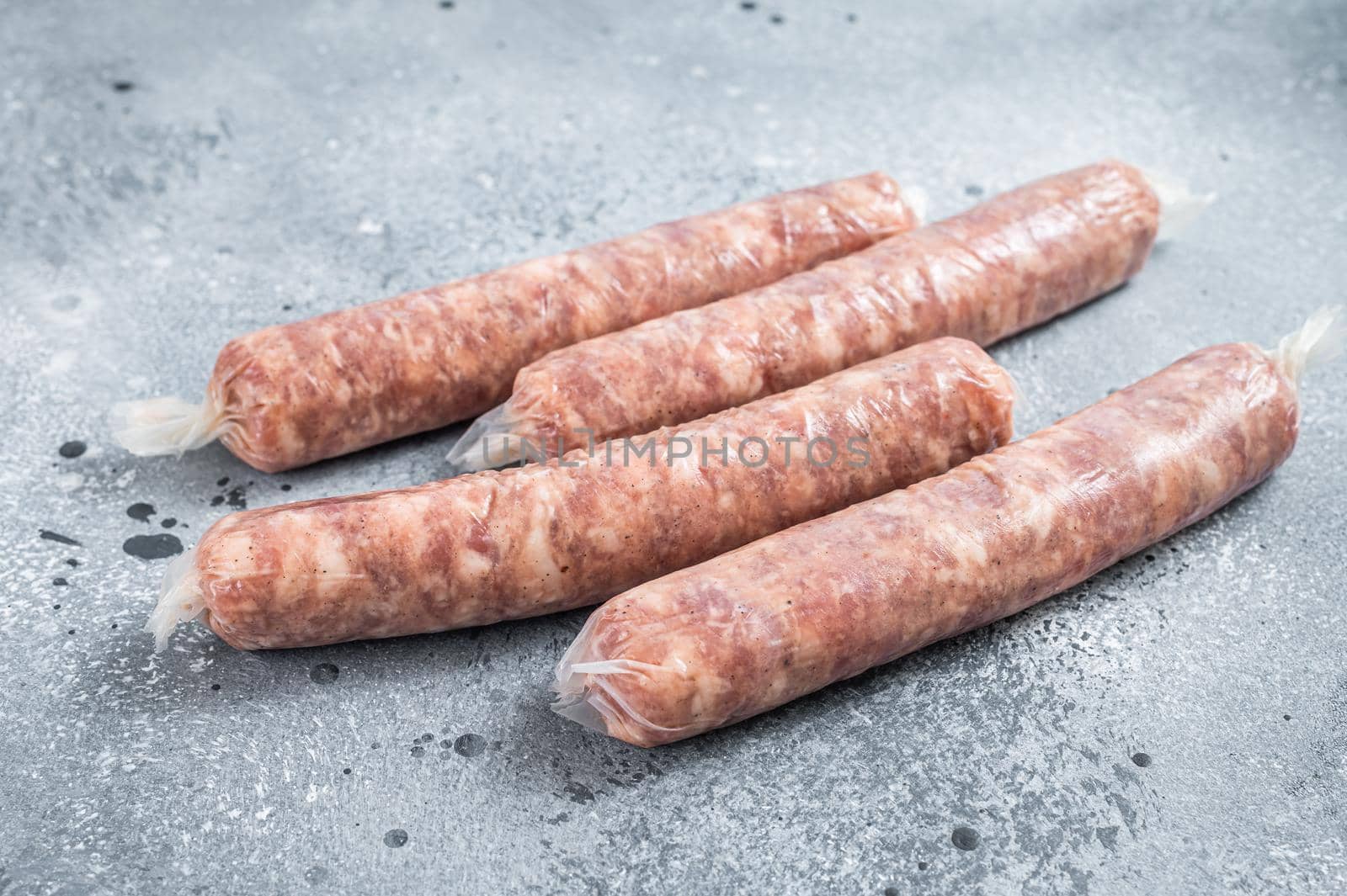 Bratwurst raw sausages on a kitchen table. Gray background. Top view by Composter