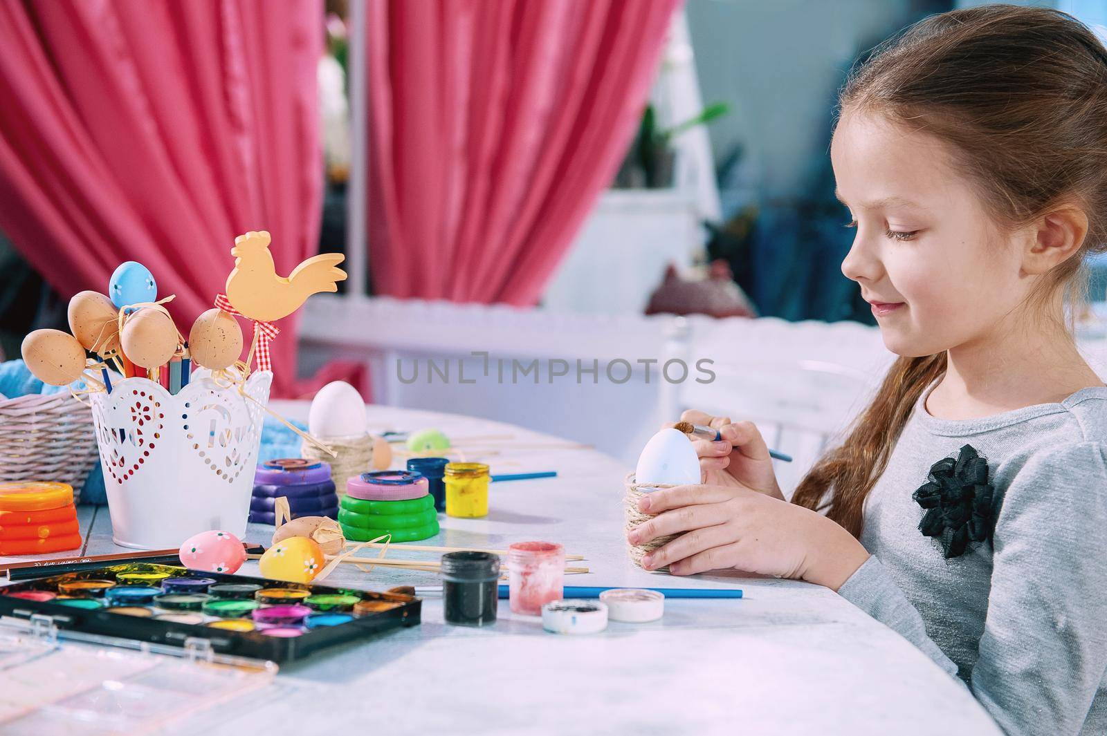 little girl paints an Easter egg