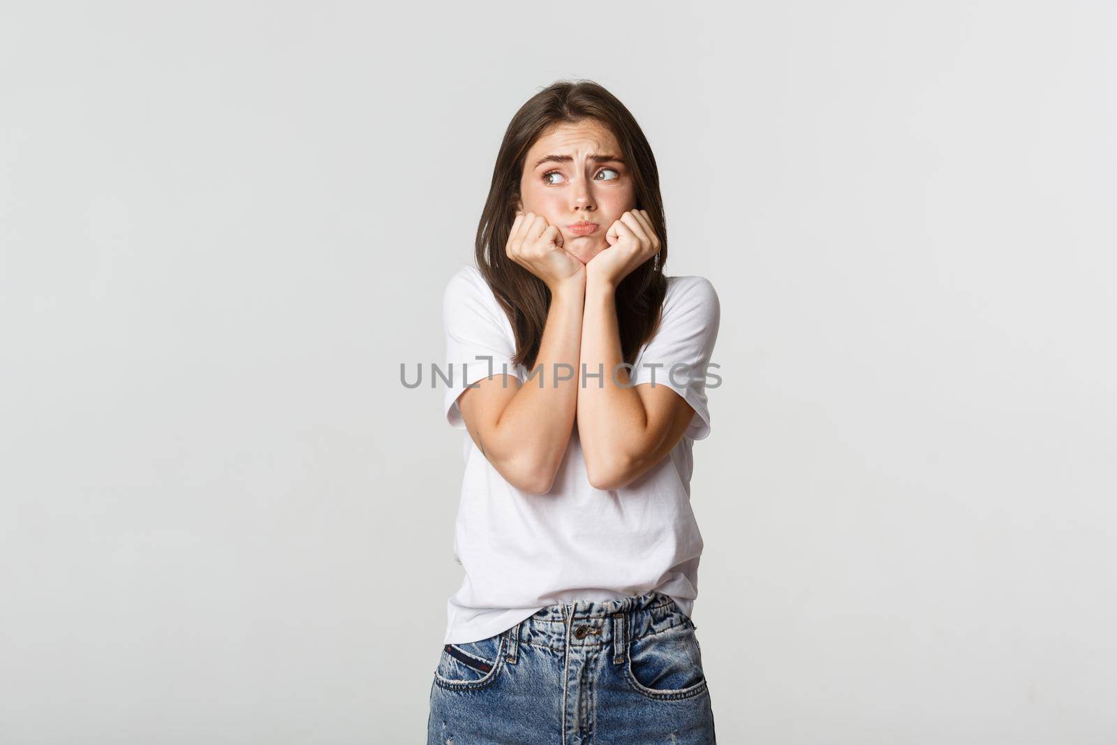 Nervous sad brunette girl leaning on hands and looking left miserable.