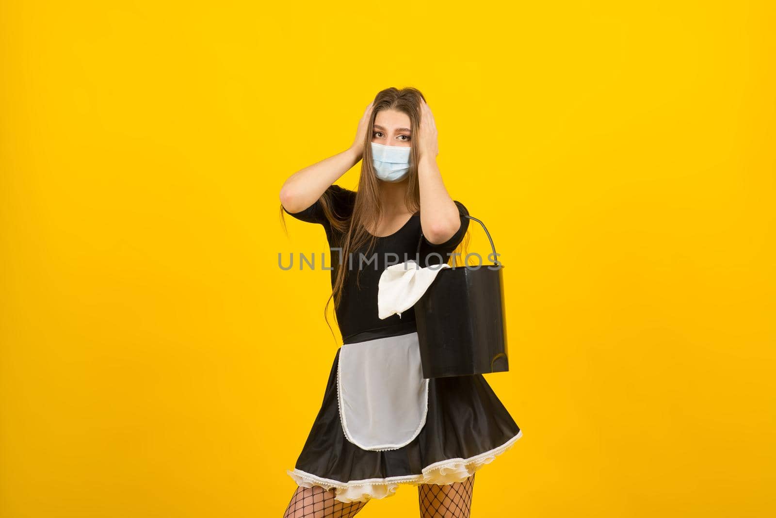 Beautiful sexy woman in maid clothes posing in studio in covid protective mask