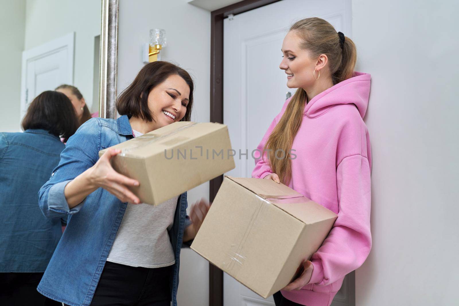Delivery of goods, social services, post, home, lifestyle, online shopping. Two women with cardboard boxes near the front door of the house