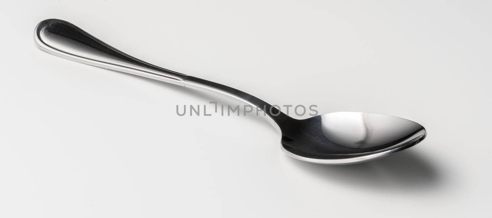 Silver dessert spoon cutlery on grey background. Close up.