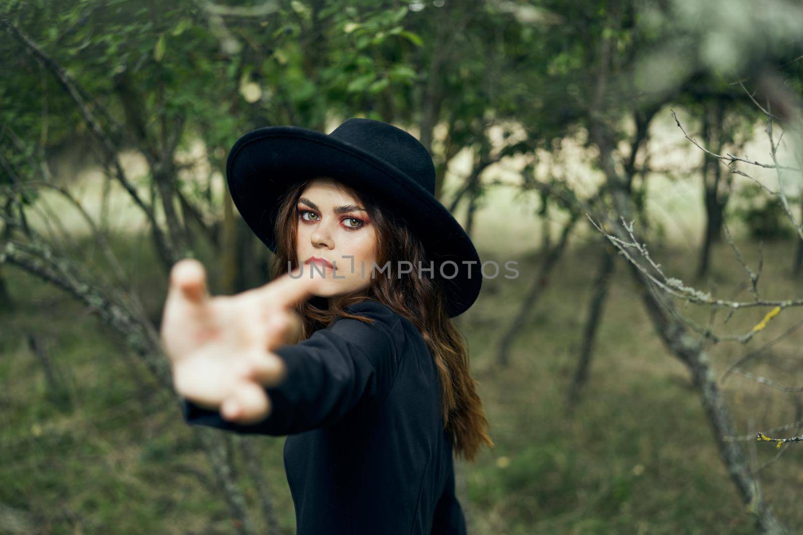 woman in a black hat gesturing with her hands witch magic fantasy. High quality photo