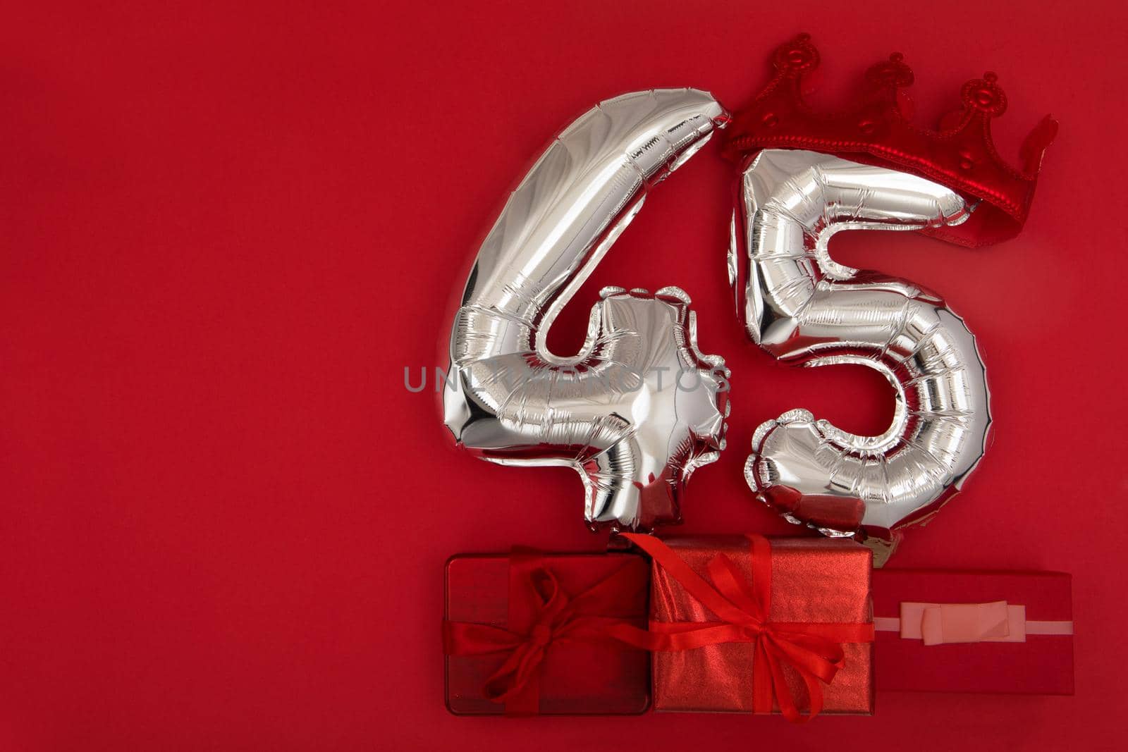 Silver Number Balloons 45 forty five in crown on dark red background. Holiday Party Decoration, 45 postcard concept with top view