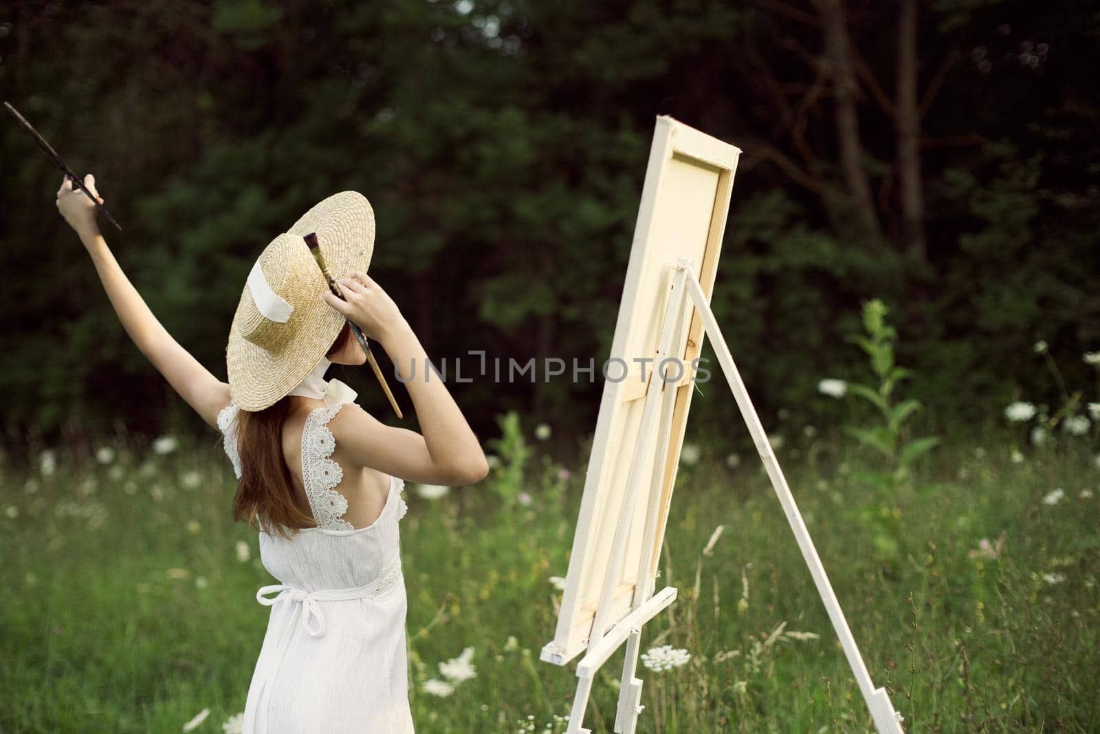 pretty woman artist paints a picture on nature landscape. High quality photo