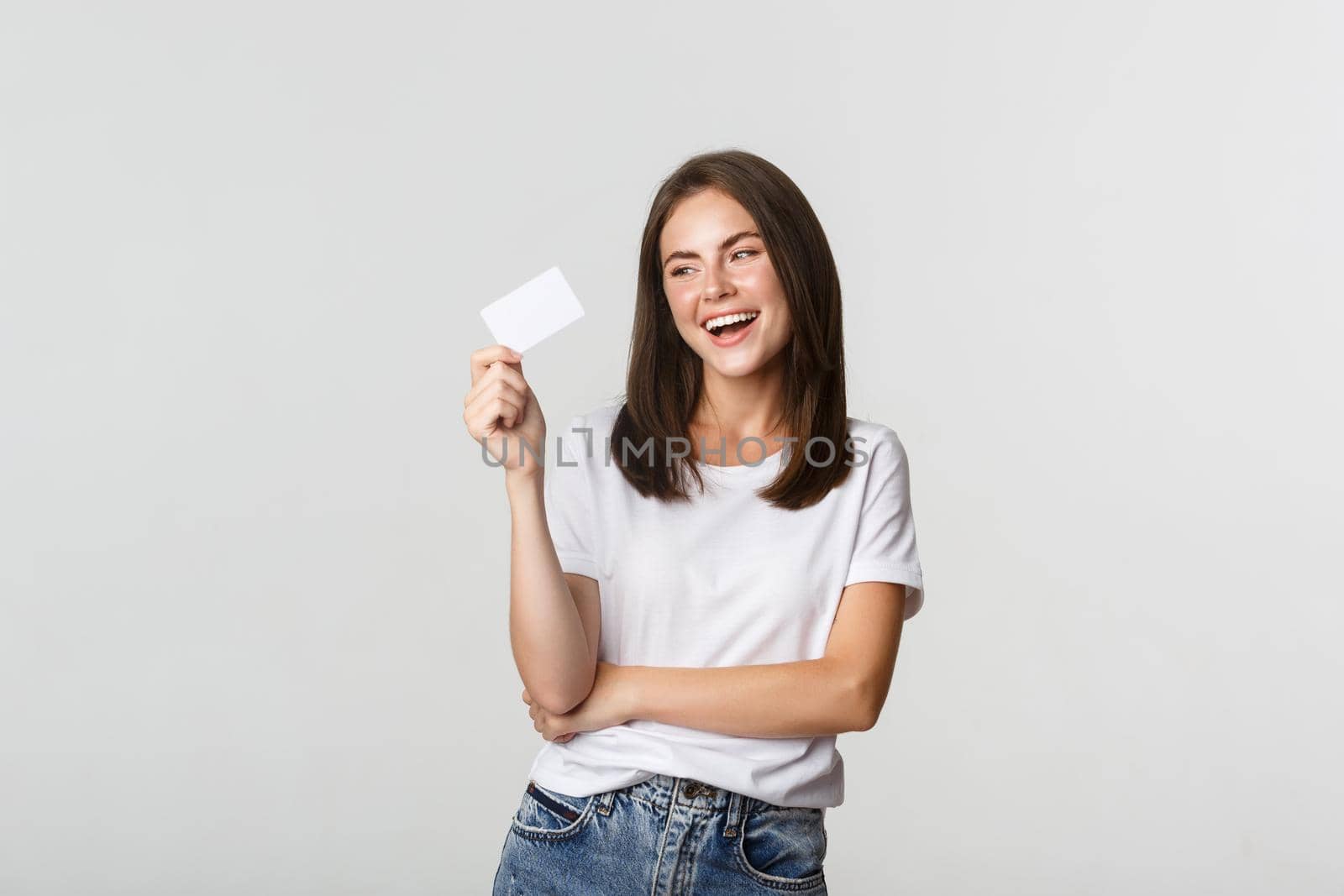 Attractive happy brunette girl laughing and holding credit card, white background by Benzoix