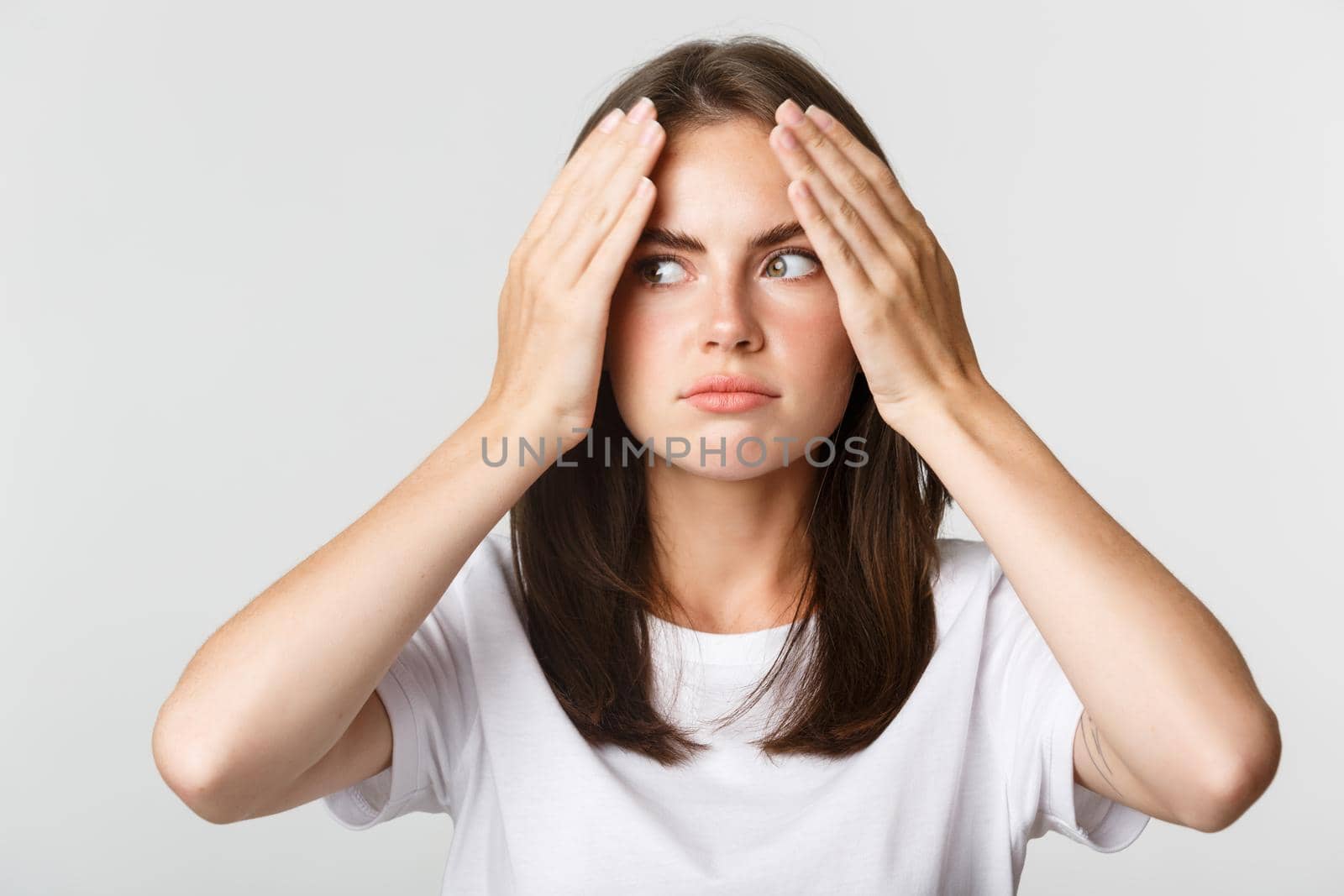 Close-up of embarrassed and shocked young beautiful woman facepalm and looking awkward, white background.