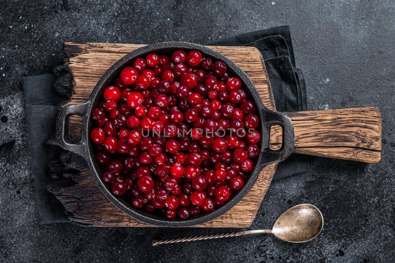 Red fresh Cranberry berry in a pan. Black background. Top view.