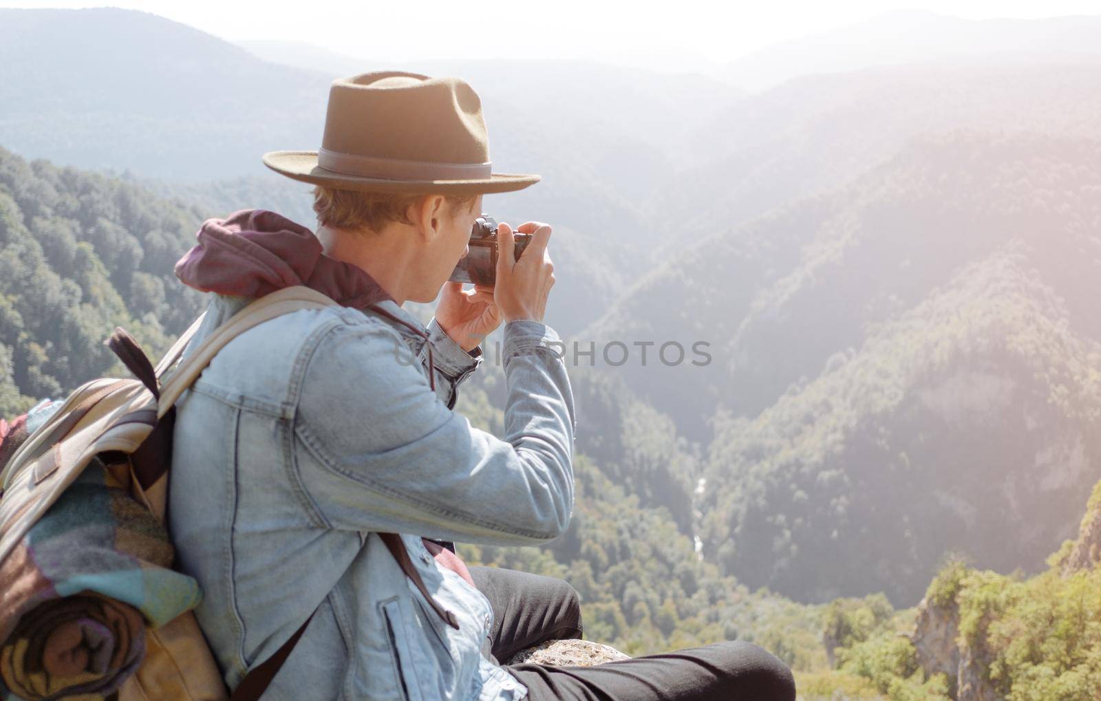 Traveler young man takes pictures with photo camera of the landscape.