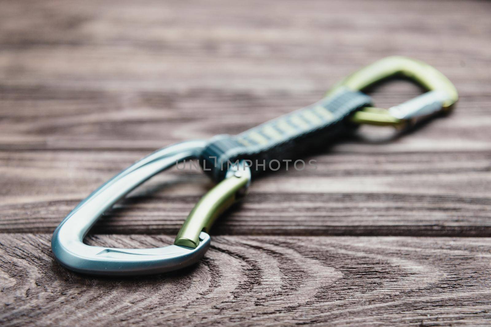 A quickdraw for climbing sport on a wooden background.