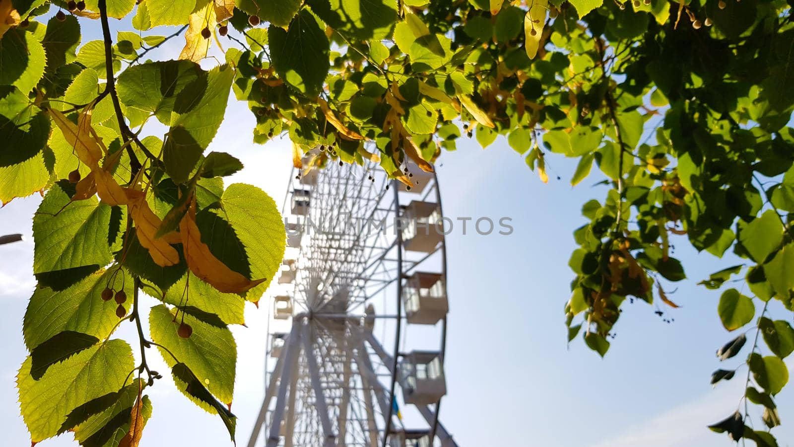 Big white ferris wheel against the blue sky. Part of the attraction on a blue background with copy space. Cabins, viewing platforms