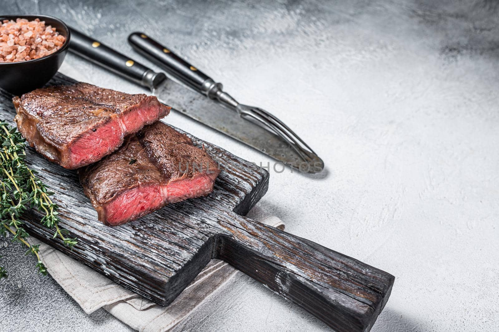 Roasted Shoulder Top Blade or flat iron beef meat steaks on wooden board. White background. Top View. Copy space.