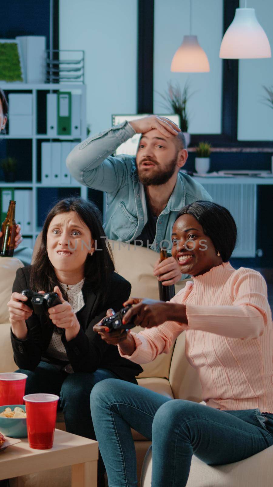 Colleagues losing at video games on console after work, playing with controllers. Diverse workmates enjoying game with joysticks on television to do fun activity and leisure at office.