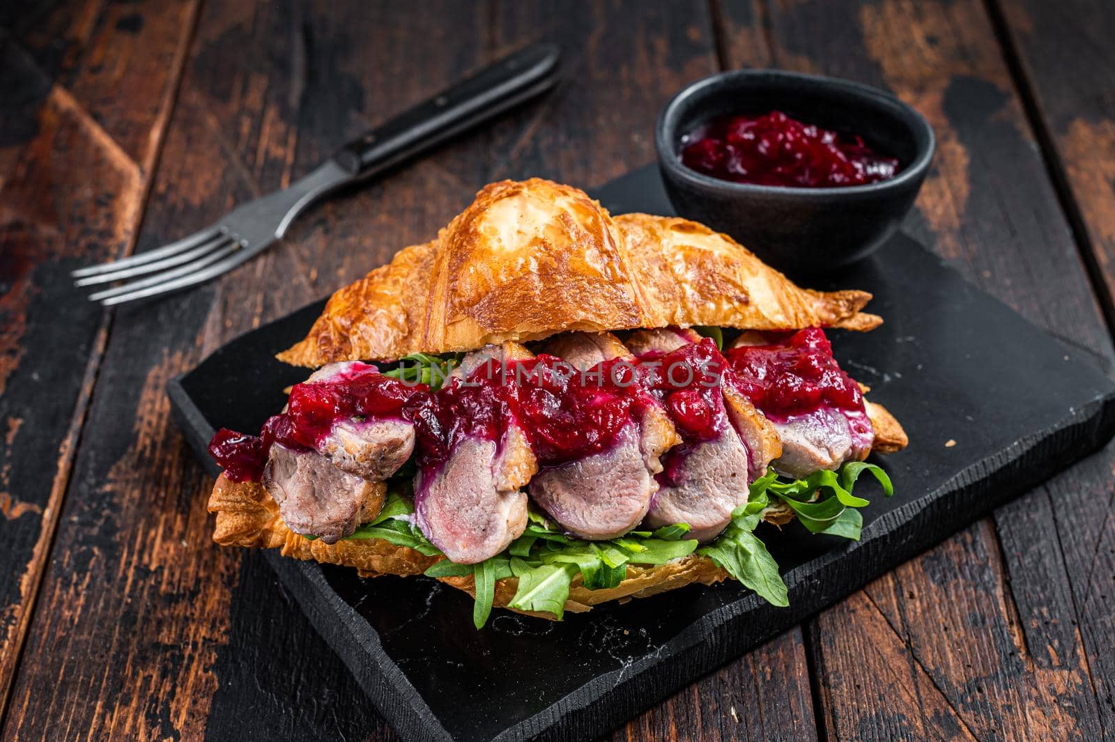 Sandwich with Duck breast fillet steak slices, arugula and sauce. Dark wooden background. Top View.