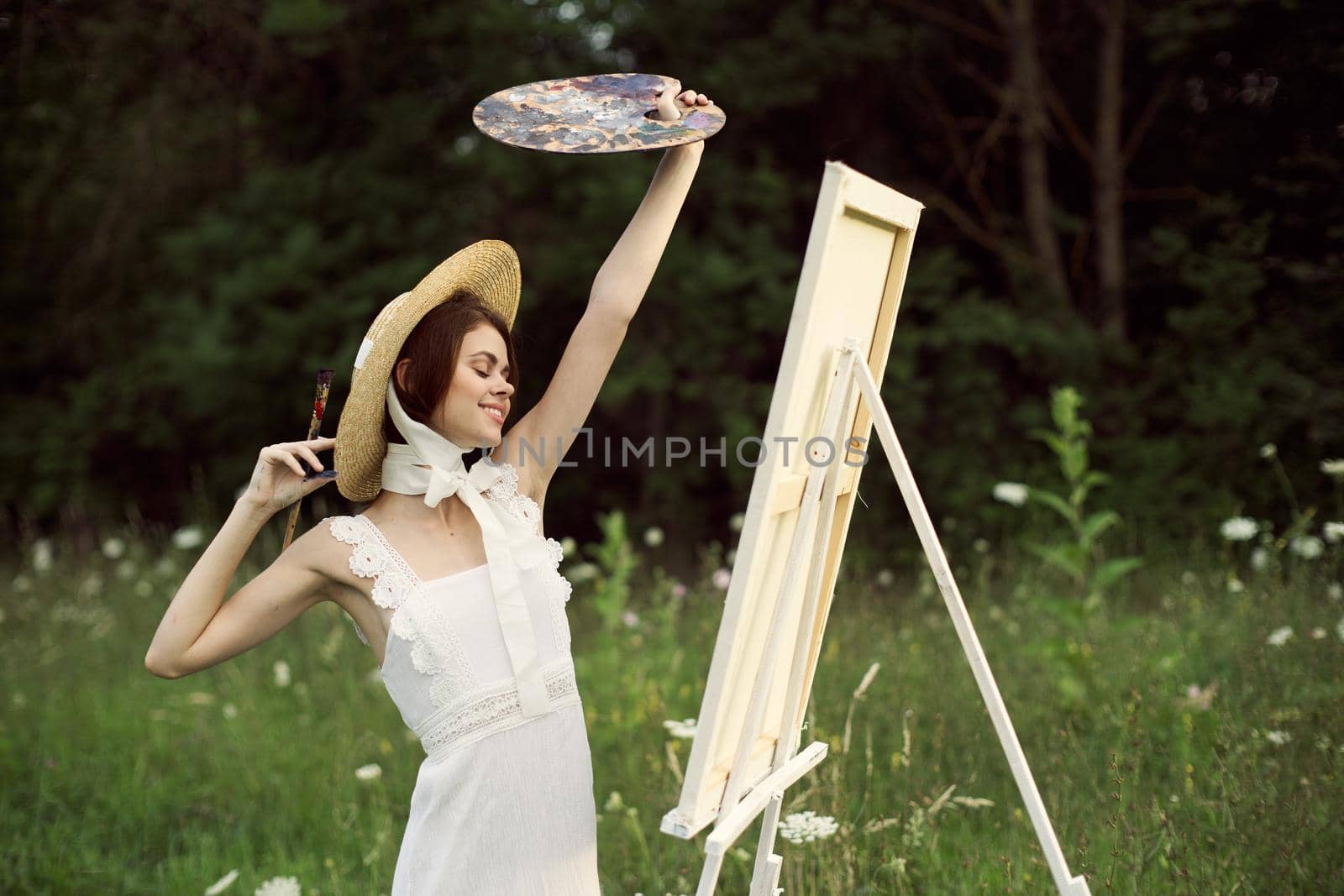 pretty woman artist paints a picture on nature landscape. High quality photo