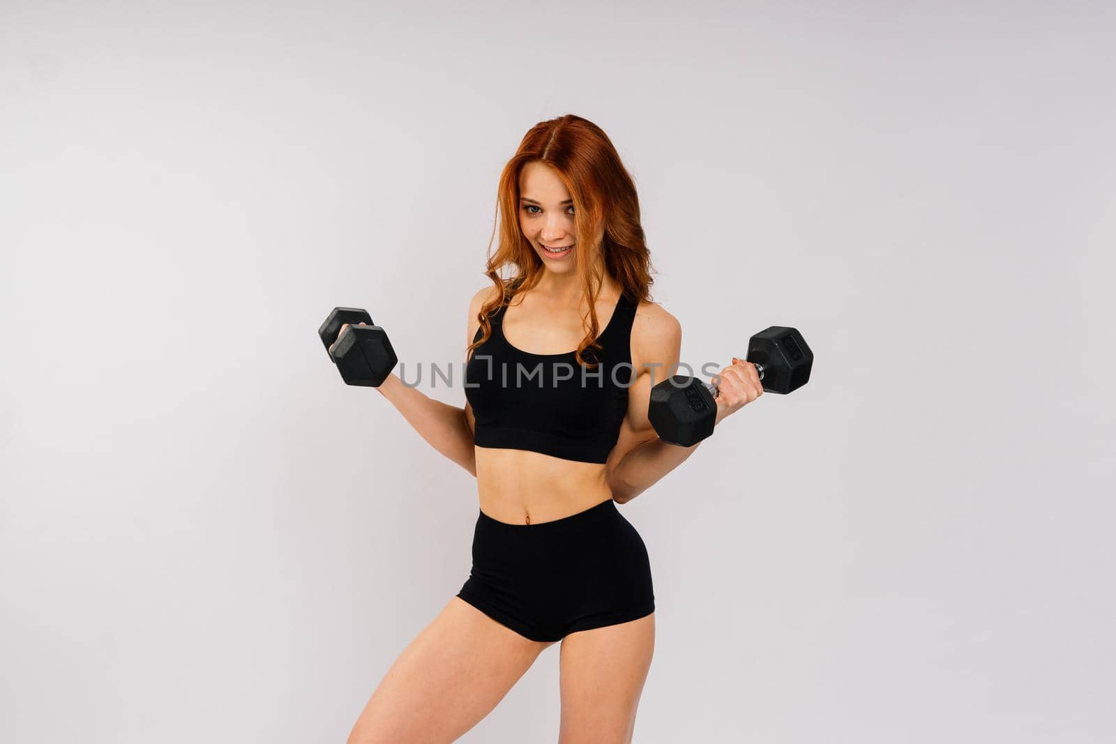 Young beautiful sporty muscular woman, isolated against white and black background in studio