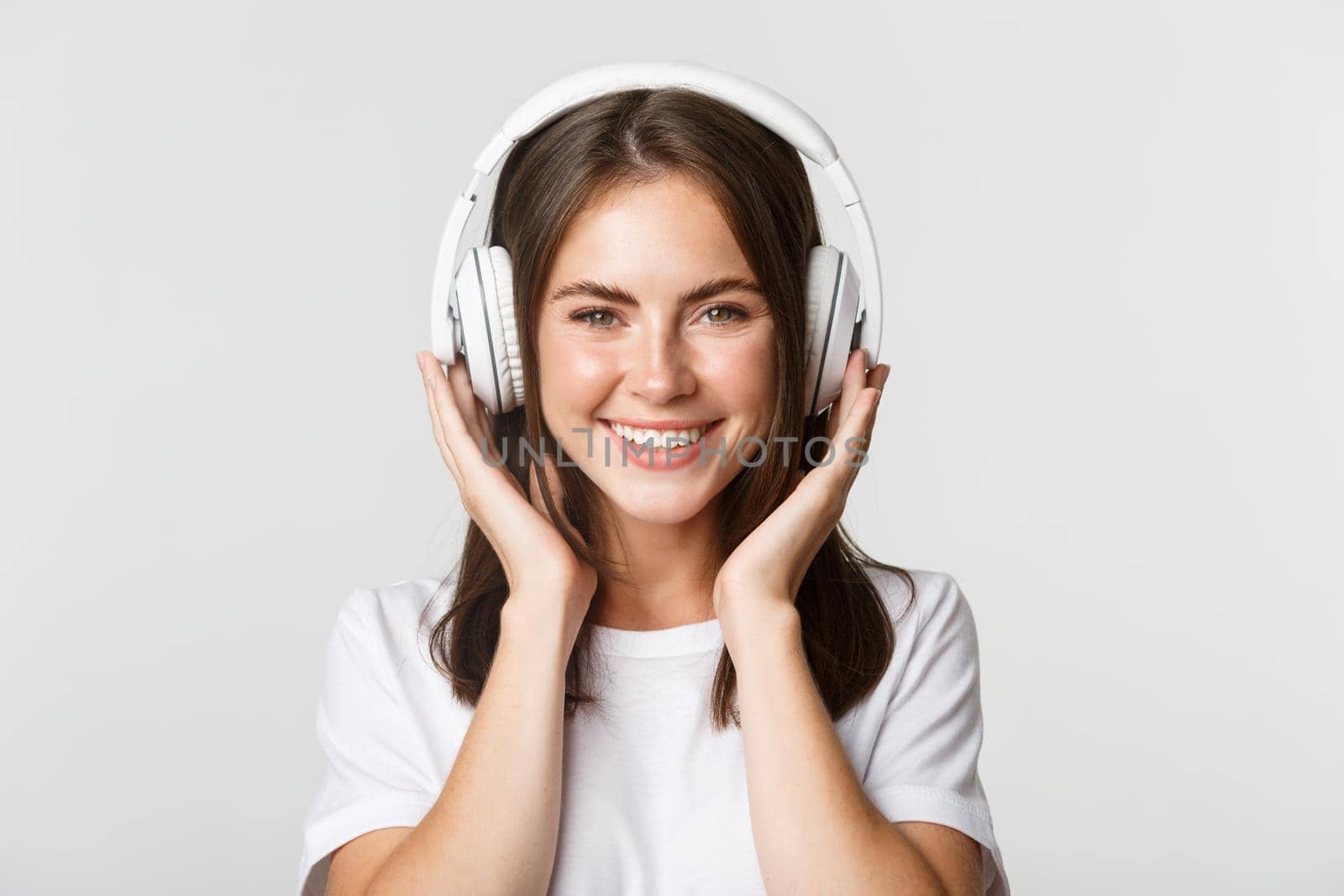 Close-up of beautiful happy girl smiling, enjoying listening music in wireless headphones by Benzoix