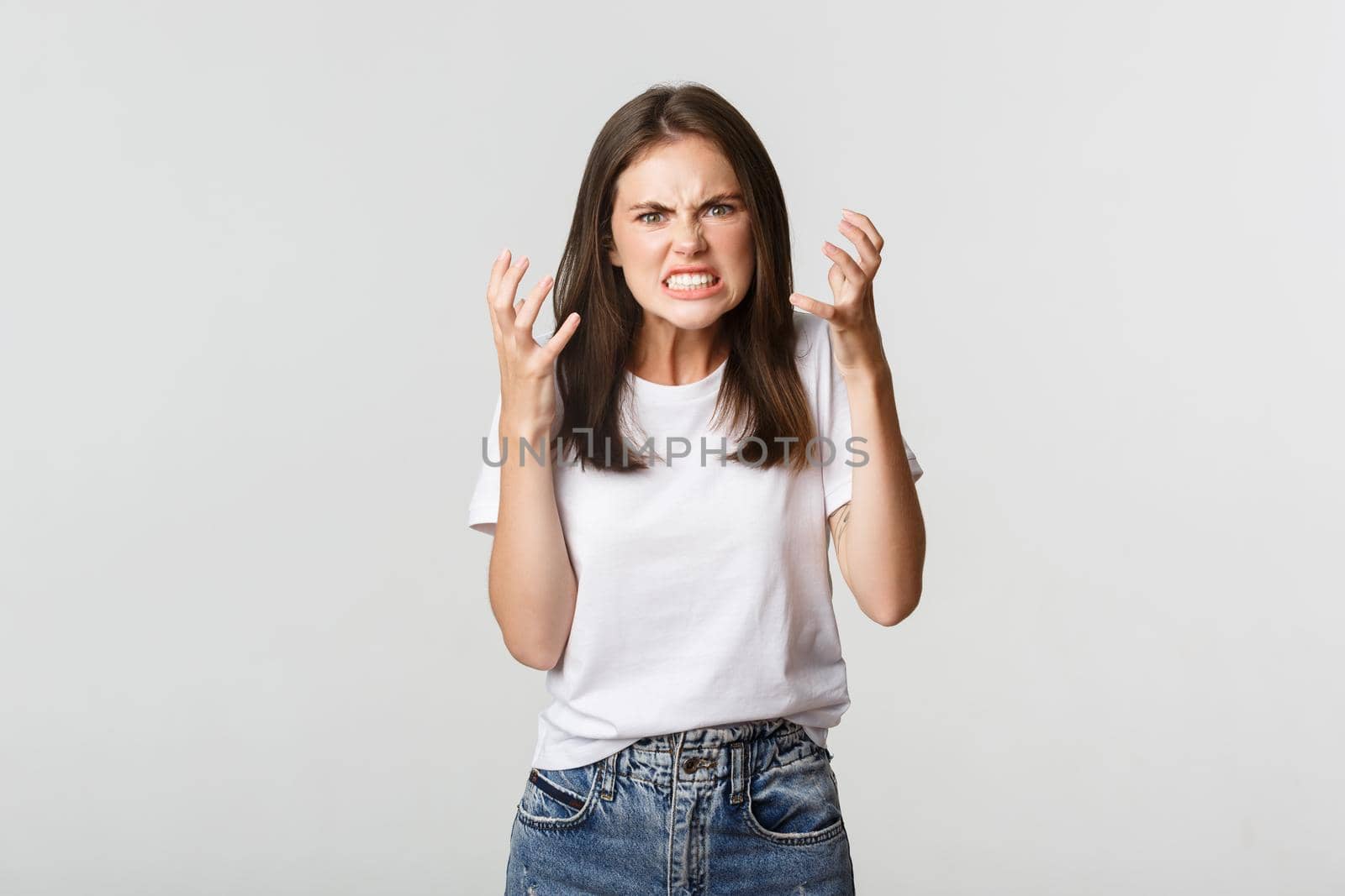 Mad and furious brunette girl clenching hands and grimacing angry.