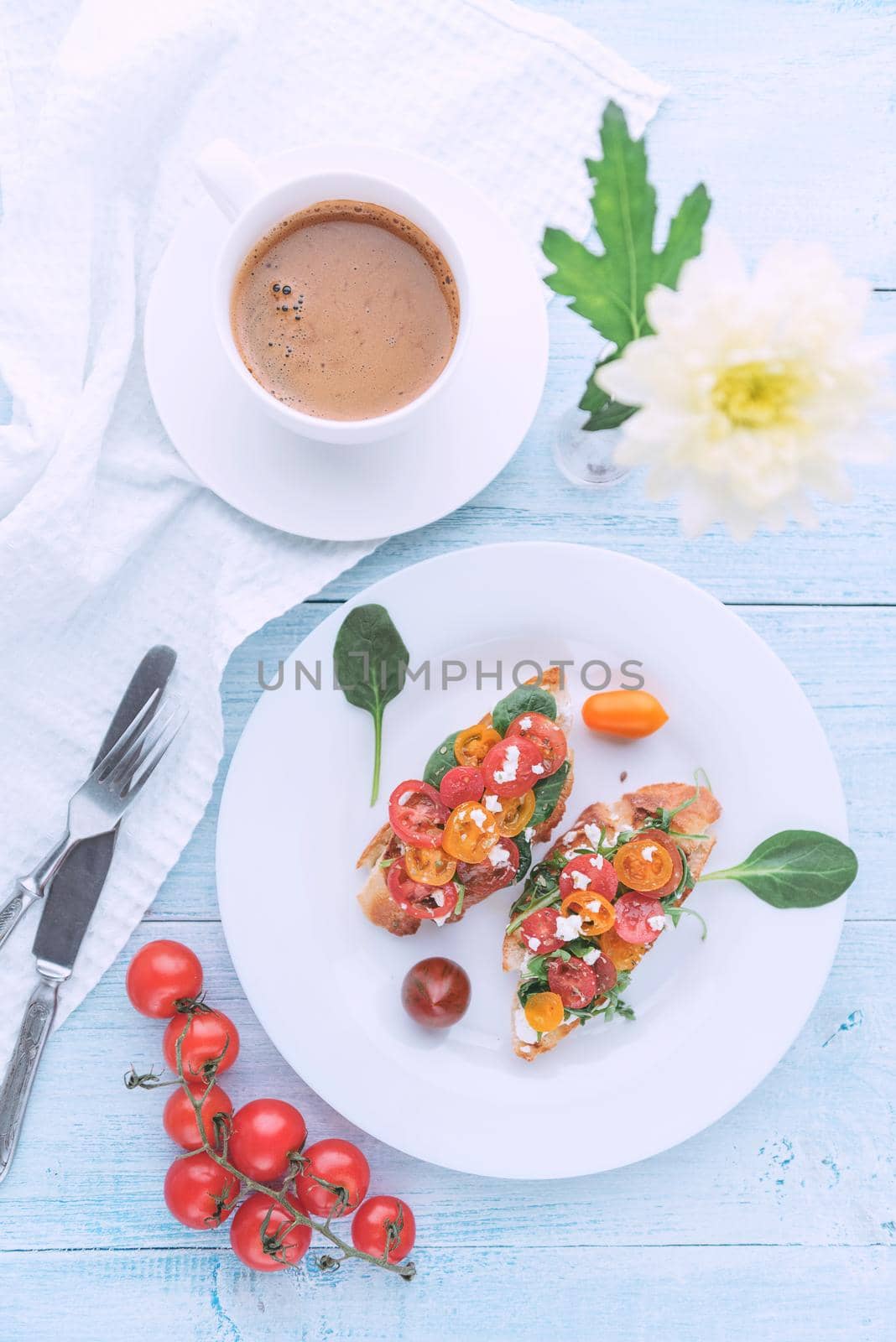 Bruschetta with cheese, basil, arugula and cherry tomatoes and a glass of white wine by vvmich