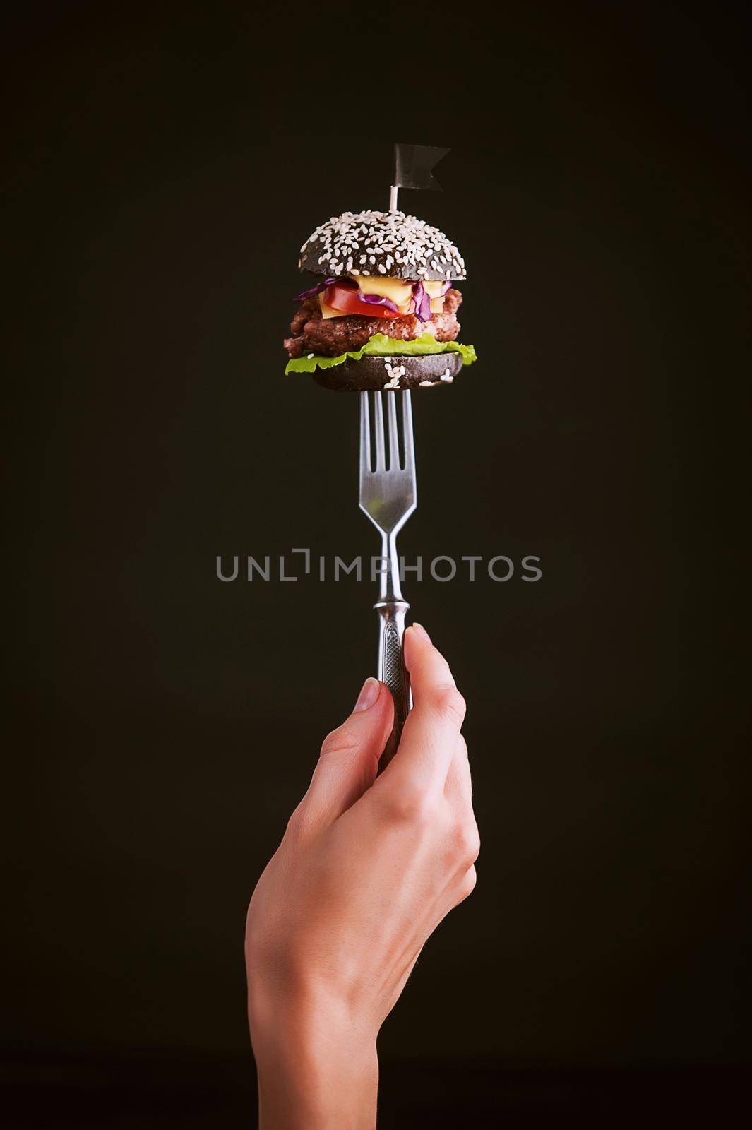 Black mini burger on the fork by vvmich