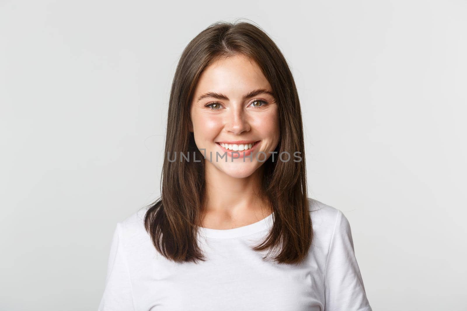 Close-up of attractive brunette girl smiling happy, standing white background.
