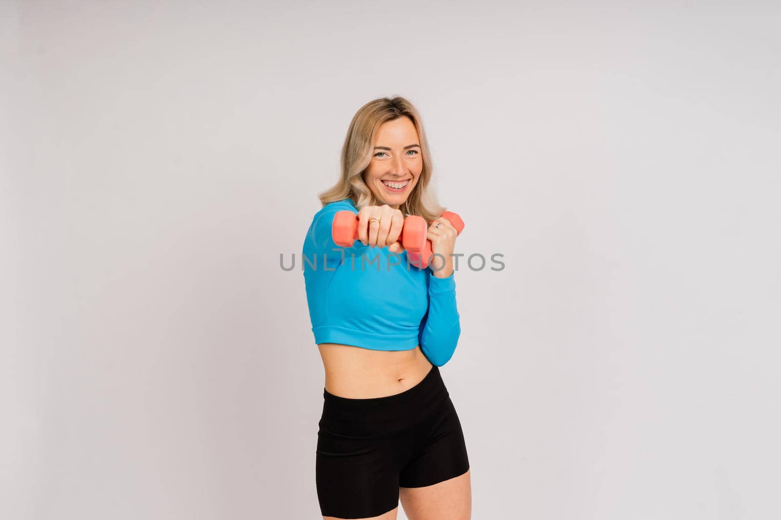 Sporty girl doing exercise with dumbbells, silhouette studio shot over dark and whitebackground by Zelenin