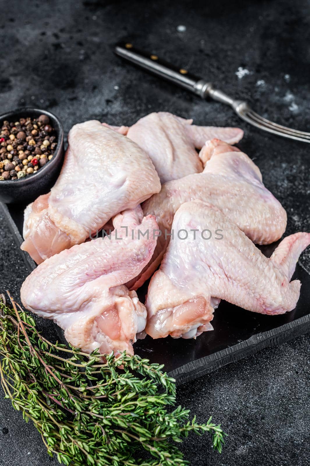 Raw chicken wings Poultry meat on a marble board. Black background. Top view by Composter