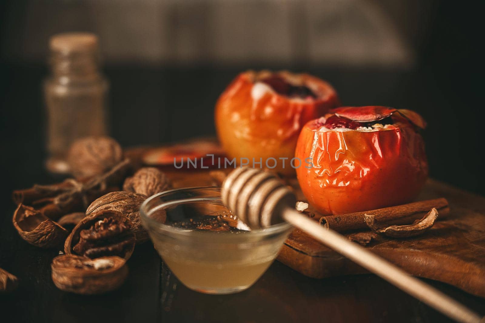 baked apples with cottage cheese with berries and nuts, topped with honey and sprinkled with cinnamon. on a wooden surface in a rustic style