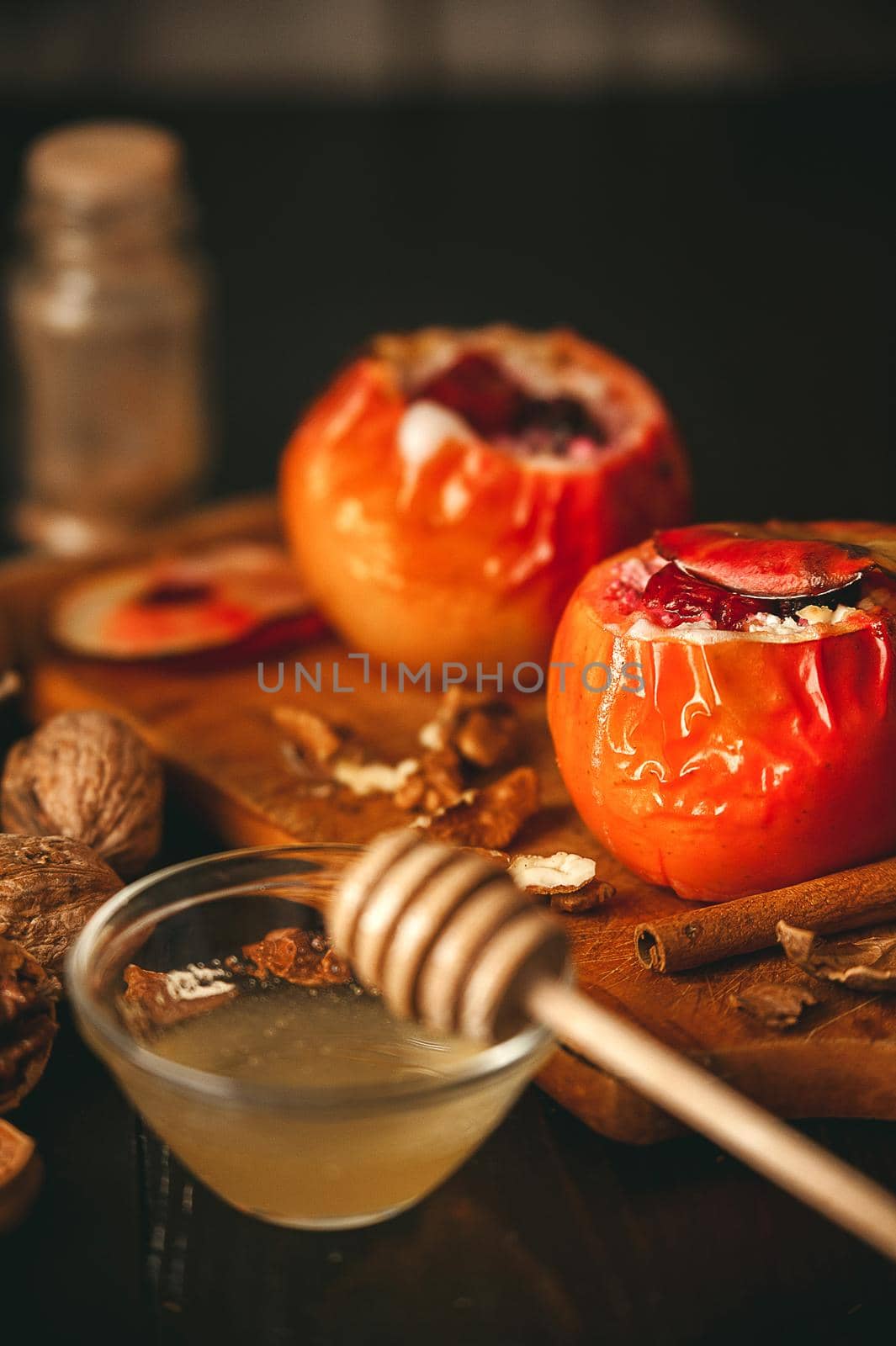 baked apples with cottage cheese with berries and nuts, topped with honey and sprinkled with cinnamon. on a wooden surface in a rustic style