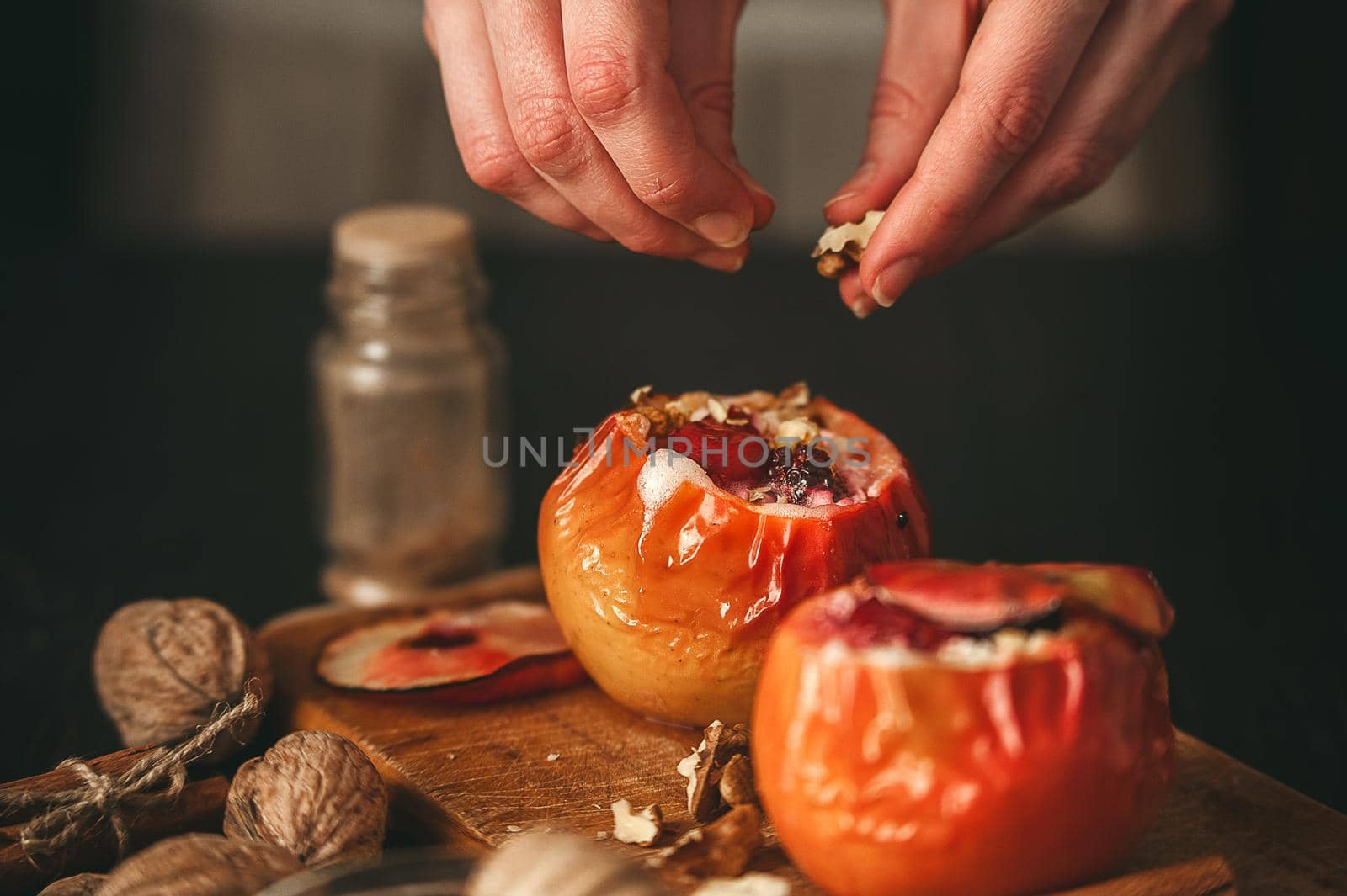 baked apples with cottage cheese with berries and nuts, topped with honey and sprinkled with cinnamon. on a wooden surface in a rustic style