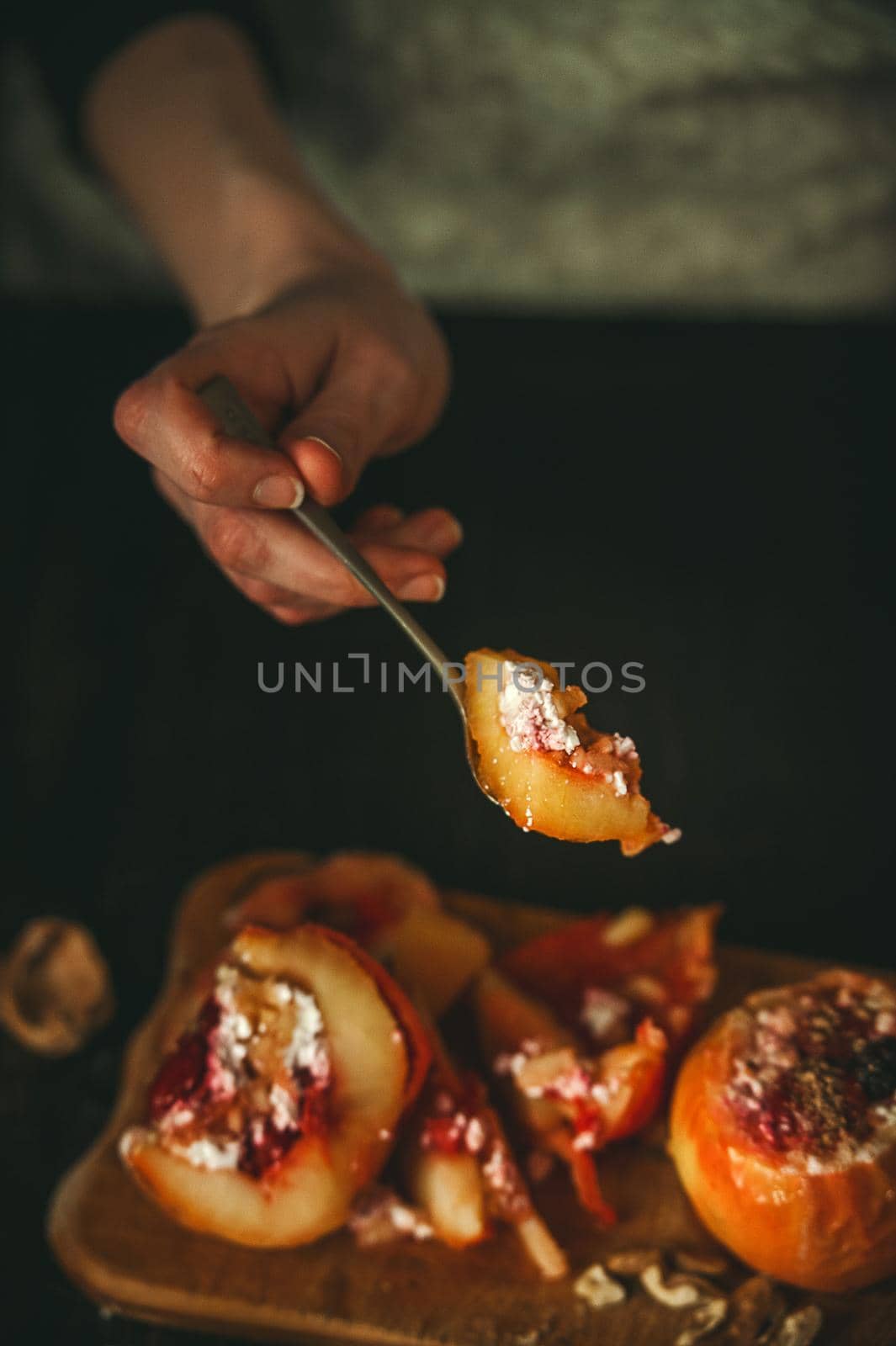 baked apples with cottage cheese with berries and nuts, topped with honey and sprinkled with cinnamon. on a wooden surface in a rustic style