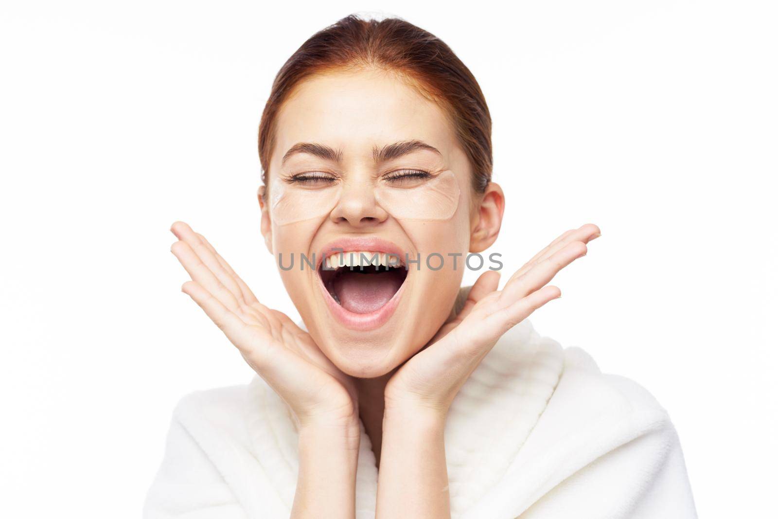 Woman in white robe posing fun skin care patches on face. High quality photo
