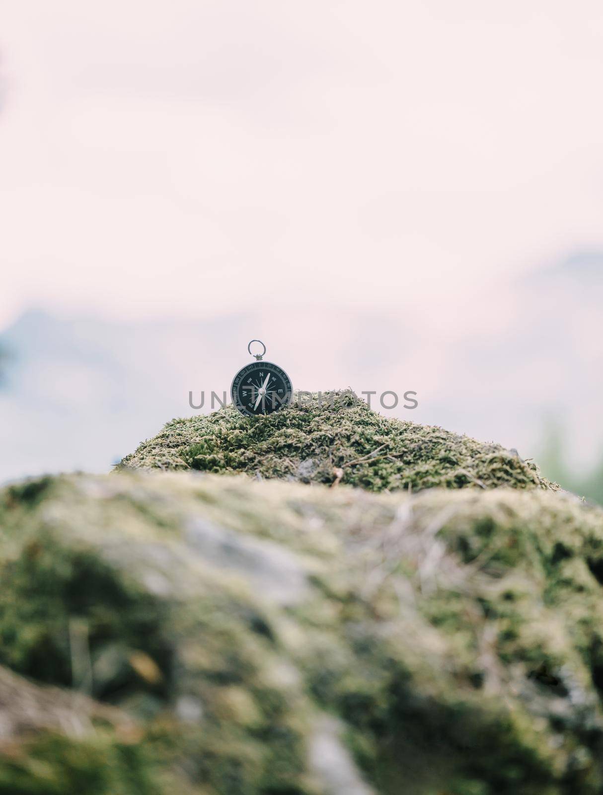 Magnetic compass on stone covered with moss outdoor, concept of travel and hiking.