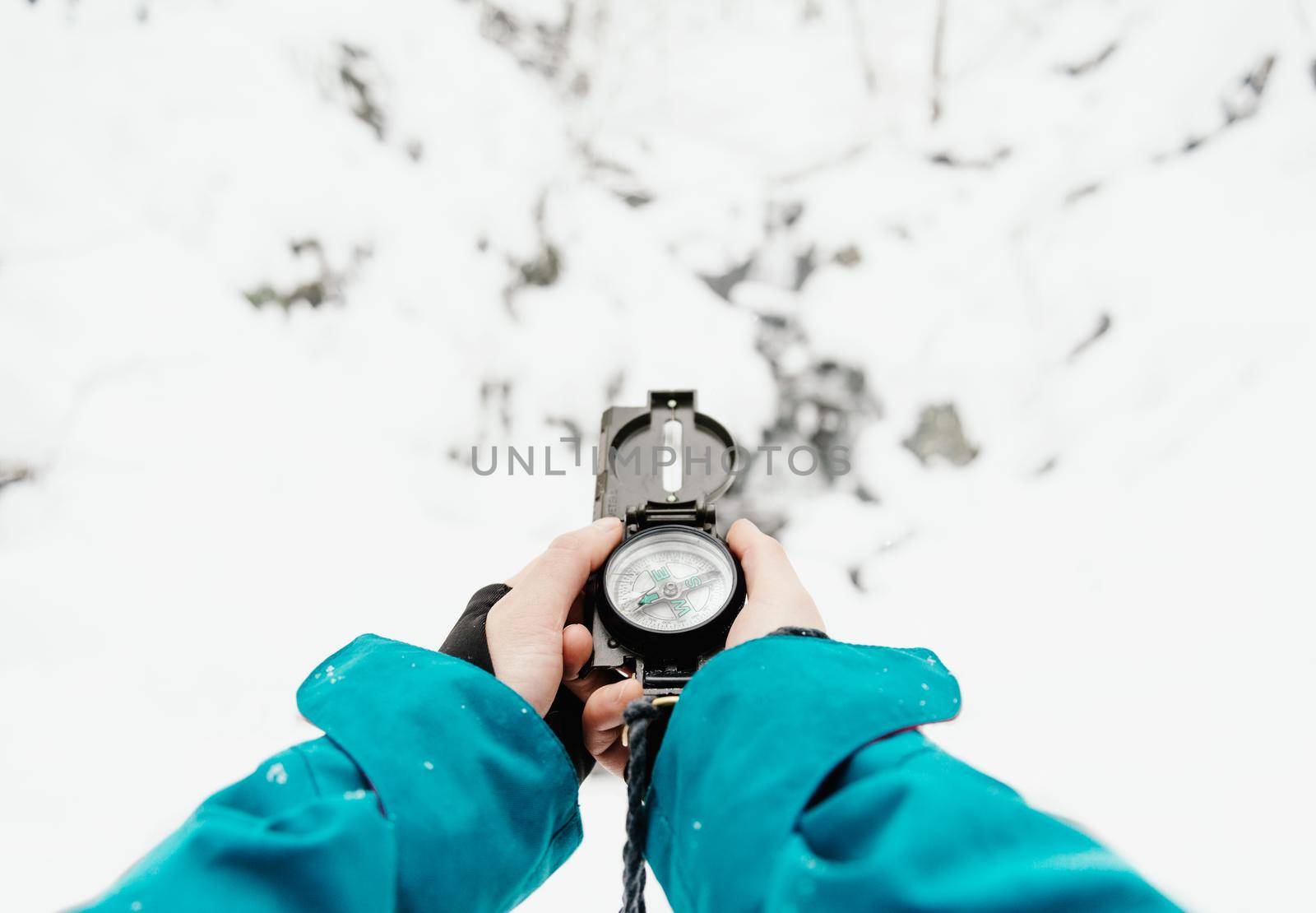 Female hands with a compass in winter outdoor on background of snow. Point of view shot.