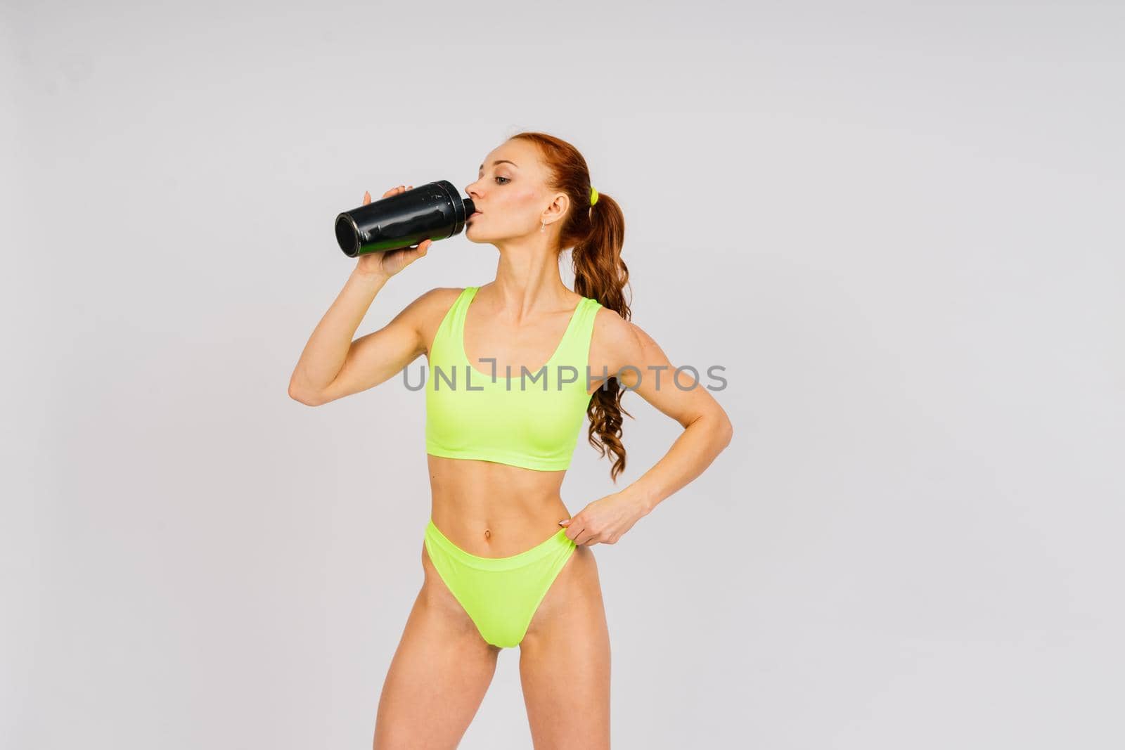 Young beautiful sporty muscular woman, isolated against white and black background in studio