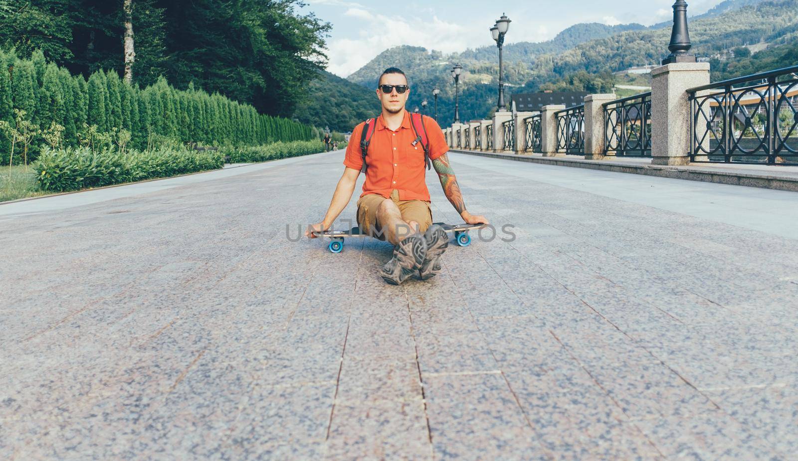 Guy sitting on longboard outdoor. by alexAleksei