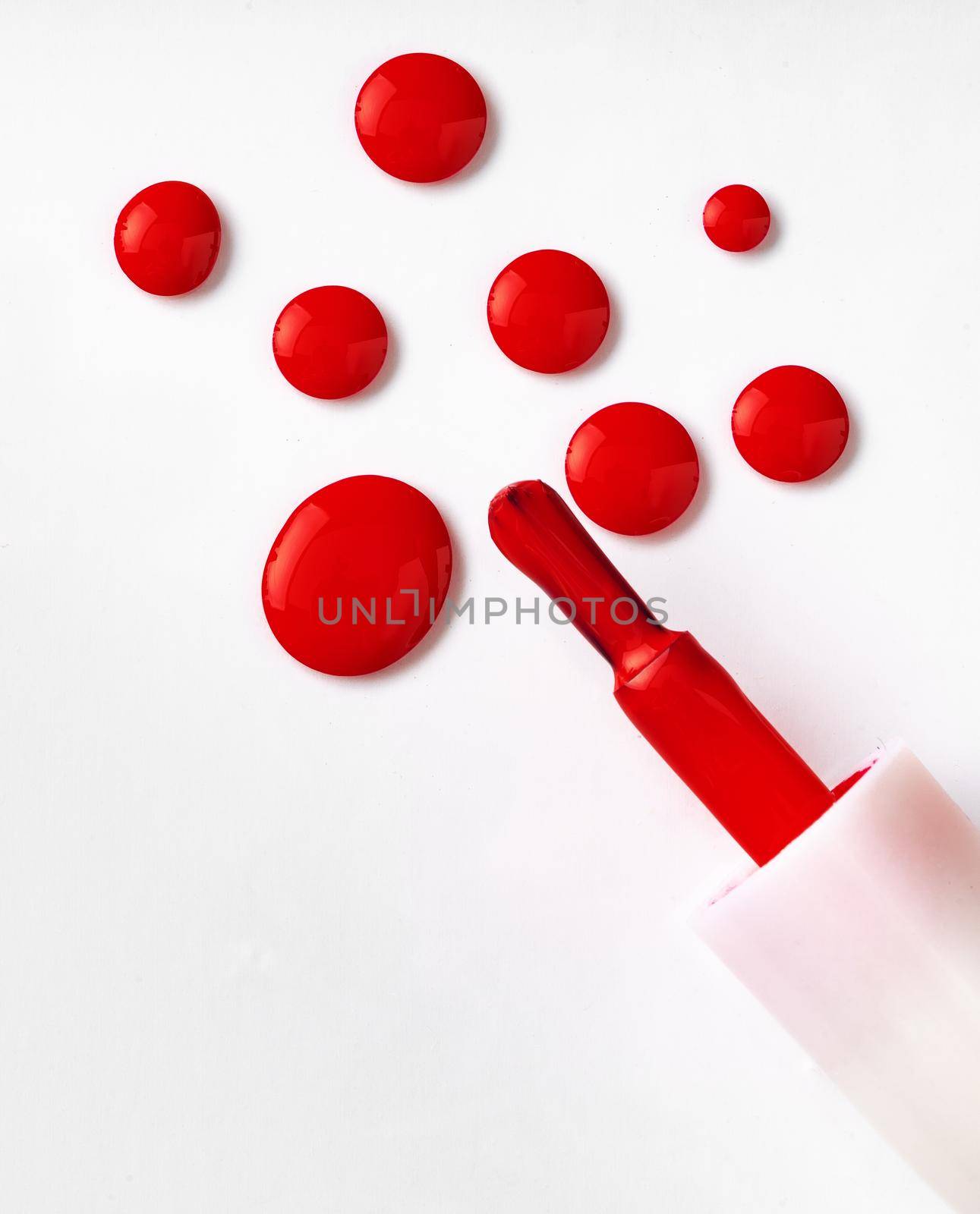 Drops of spilled nail polish over white background. Close up.