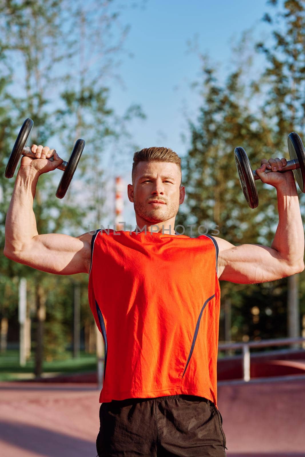 Muscled Man With Dumbbells Outdoor Workout. High quality photo