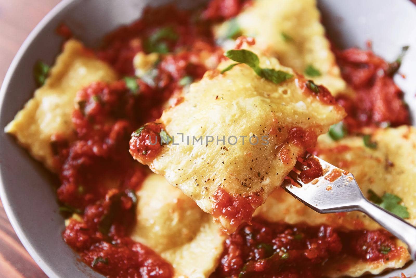 Delicious ravioli with tomato sauce in a plate on a wooden background