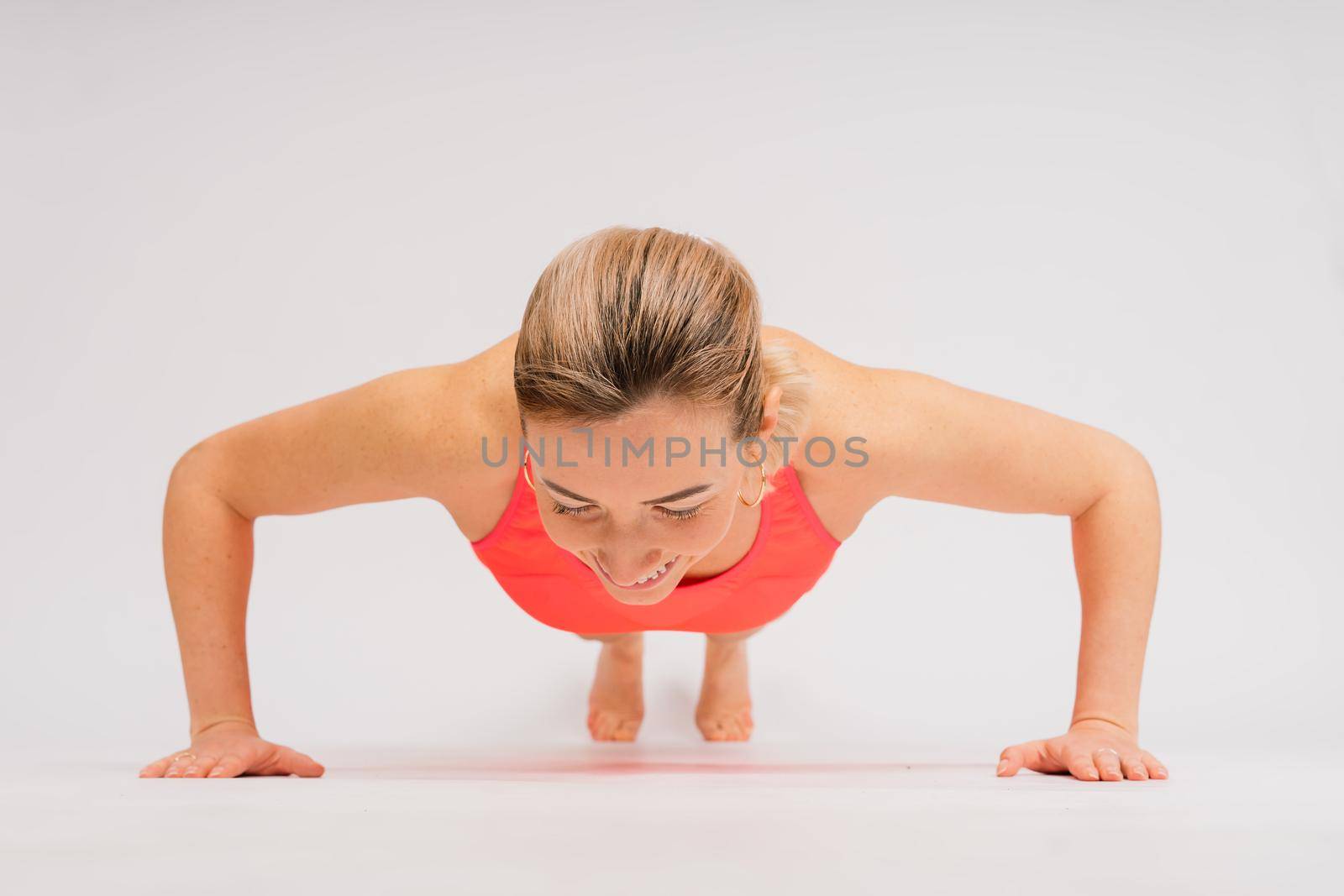 Beautiful female with dumbbells posing on studio background by Zelenin