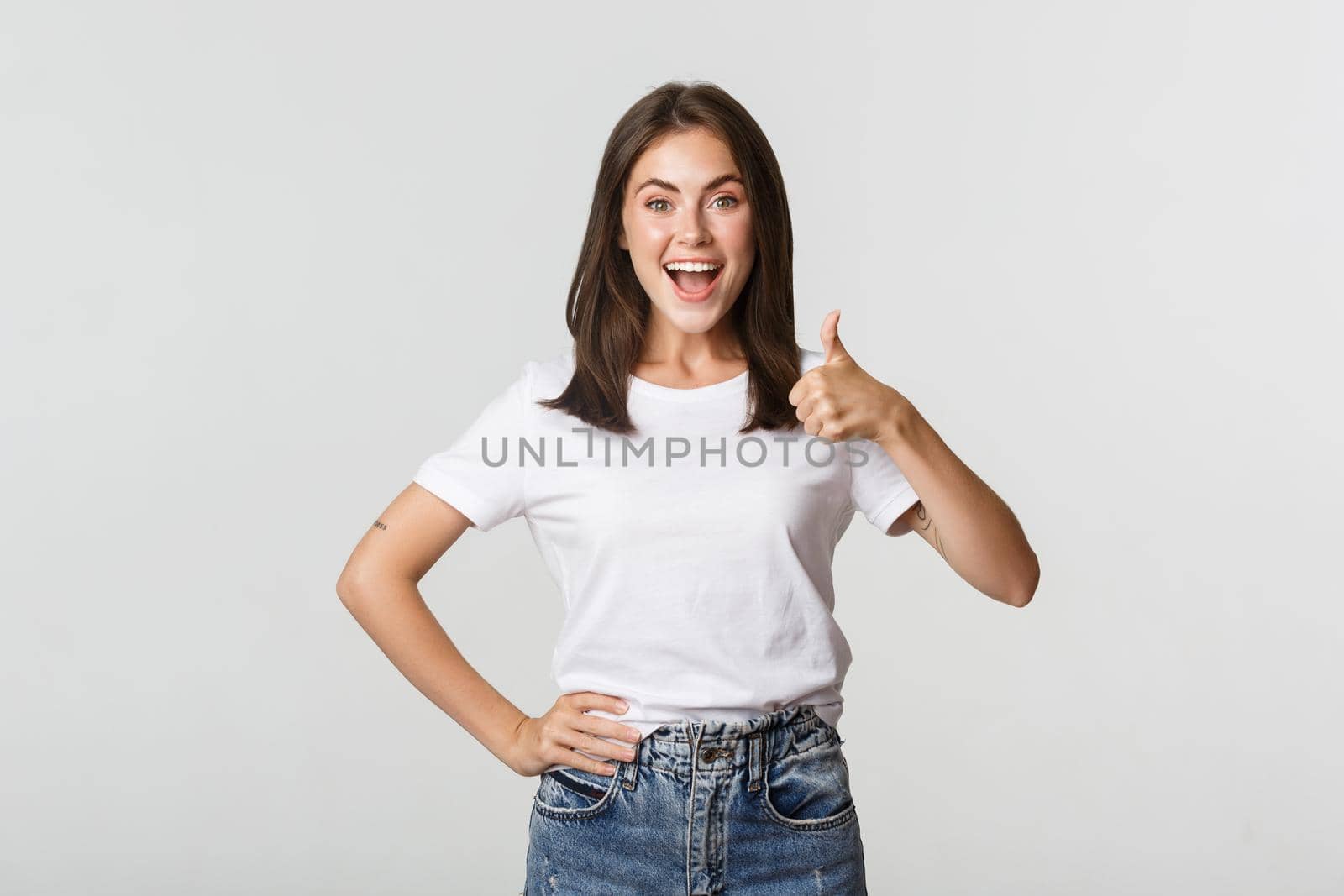 Happy satisfied young woman smiling, showing thumbs-up in approval, like something.