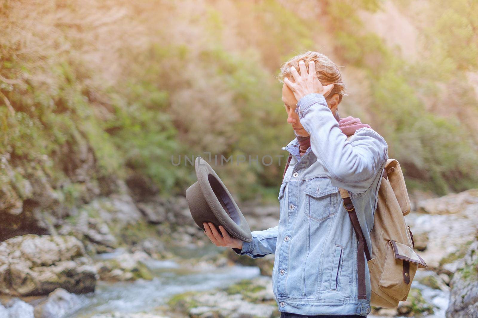 Traveler young man wearing in jeans jacket and hat walking by the river in summer.