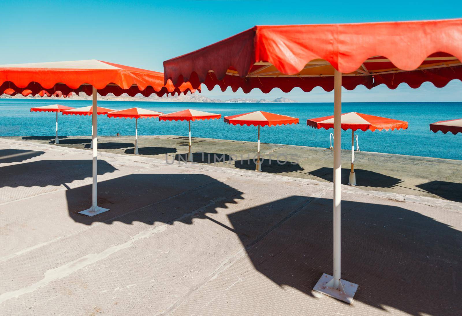 Bright red umbrellas on beach near the sea.